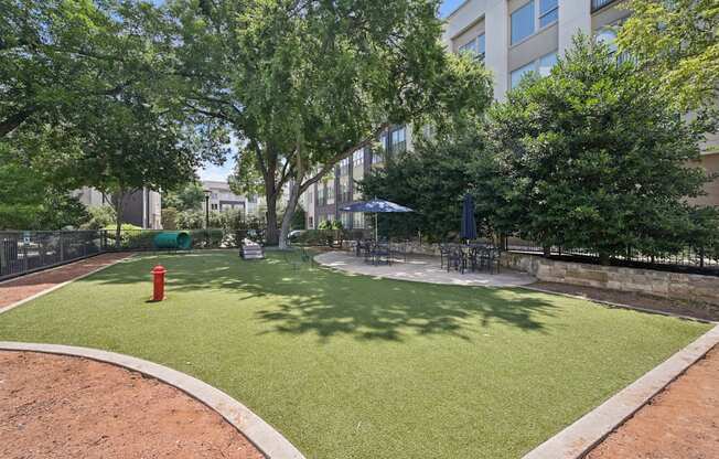 A park with a red fire hydrant and a green lawn.
