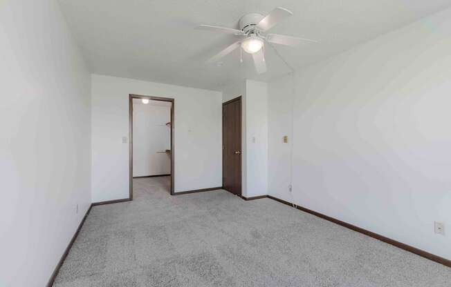 A room with a ceiling fan and carpeted floor.