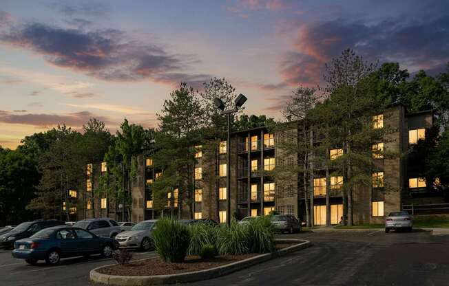 A parking lot with cars and a building with windows and trees in front.
