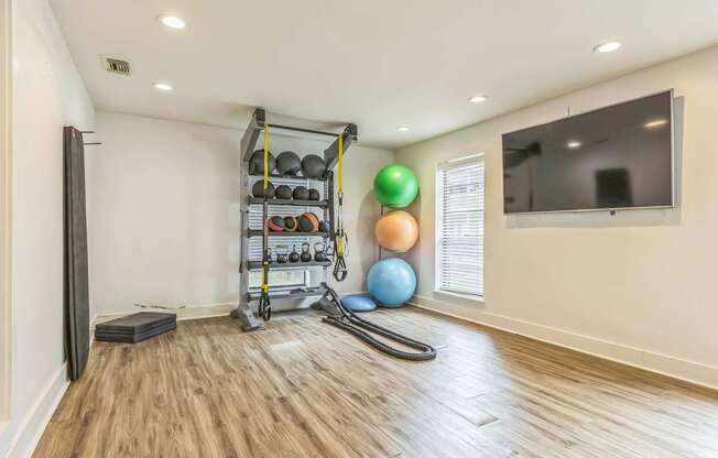 A room with a wooden floor and a wall-mounted TV.