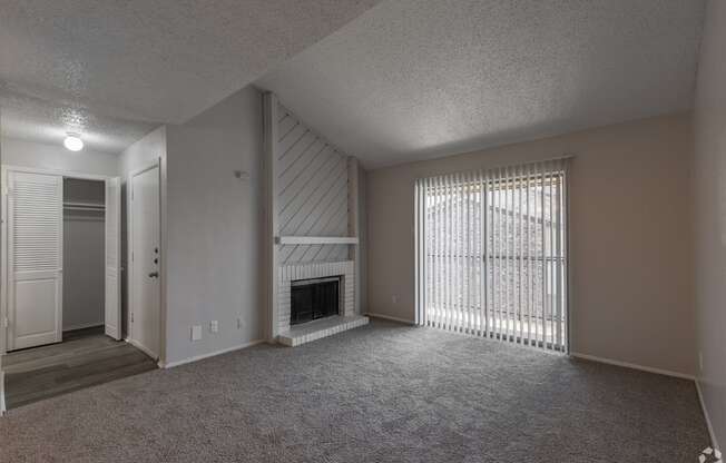 A sparsely furnished living room with a fireplace and sliding glass doors.