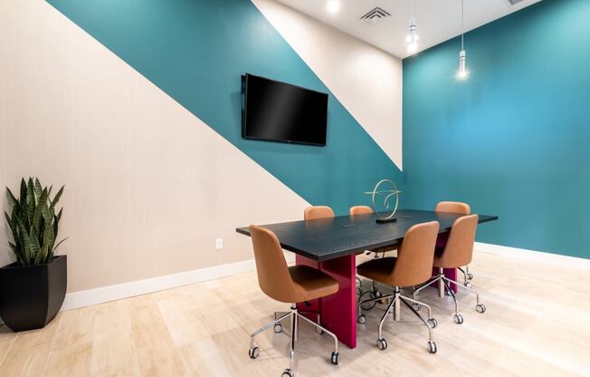 a conference room with a table and chairs and a tv on the wall