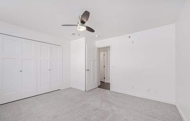 A room with a ceiling fan and carpeted floor.