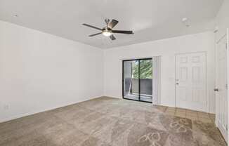 A room with a ceiling fan and a rug on the floor.