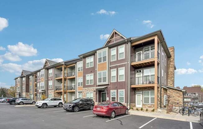 an apartment building with cars parked in front of it at The Quarry Luxury Apartment Homes, Fort Collins, CO