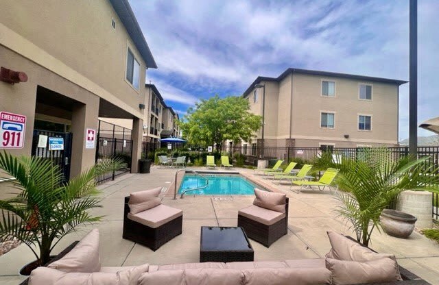 a swimming pool is next to a patio with furniture