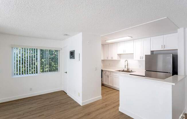 A kitchen with white cabinets and a stainless steel refrigerator.