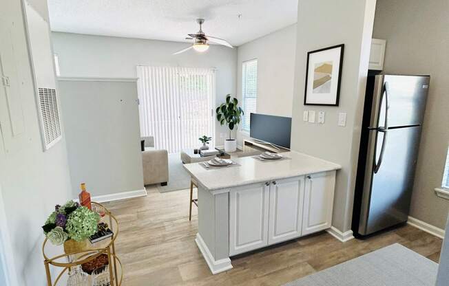 an open kitchen and living room with a refrigerator and a sink