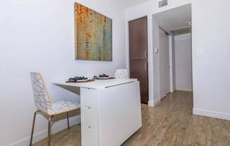 A room with a white desk and a chair with a white and orange patterned seat.
