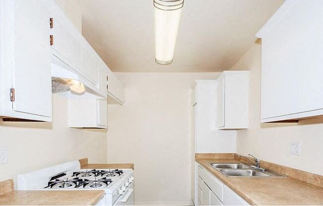 a white kitchen with a stove and a sink at Villa La Paz Apartments, California