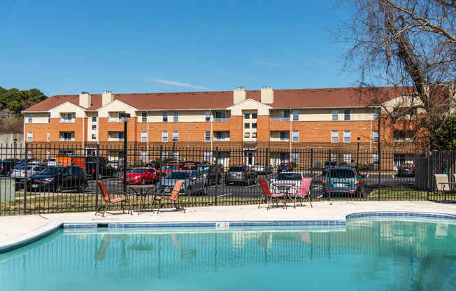 a swimming pool with chairs in front of an apartment building