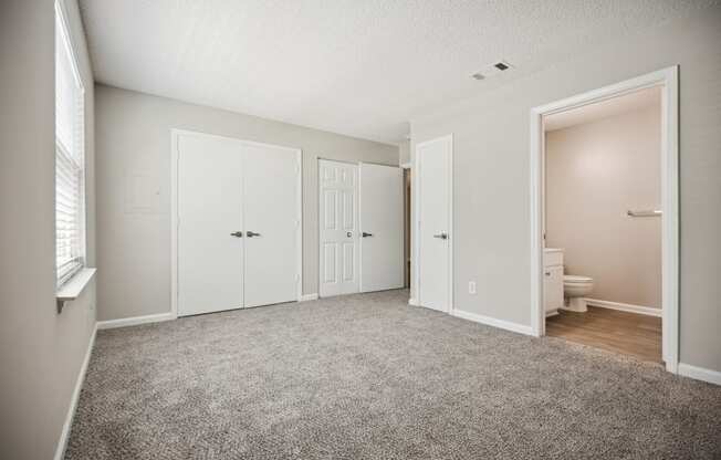 a bedroom with two doors and a bathroom in the background