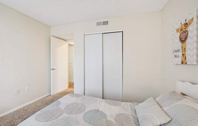 A bedroom with a bed and a giraffe poster on the wall.