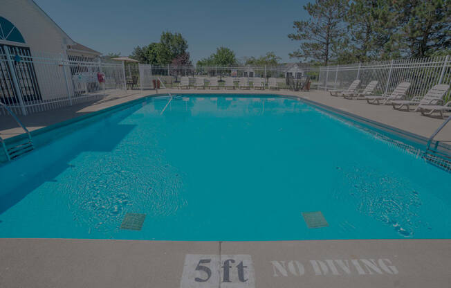 a large pool with chairs and a fence around it