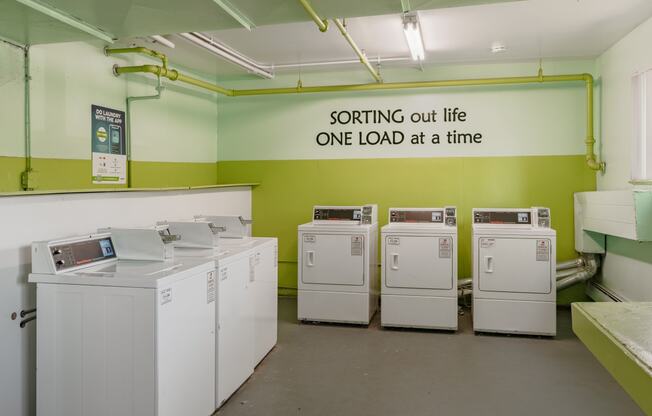 a laundry room with four washing machines and a sign on the wall