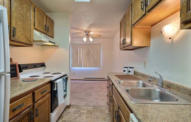 a kitchen with white appliances and wooden cabinets. Fargo, ND Pacific South Apartments