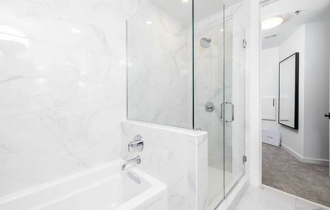 A white marble bathroom with a glass shower door.