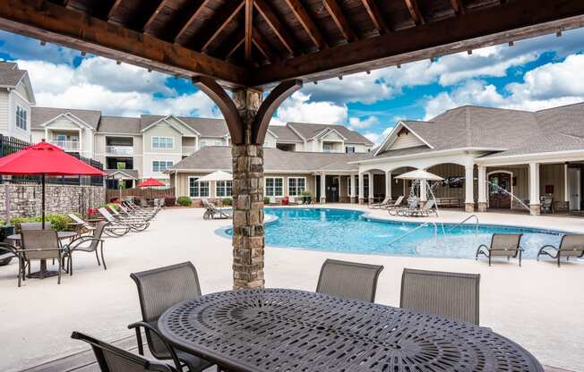 View of outdoor swimming pool and clubhouse under the poolside pavilion at Riverstone apartments for rent in Macon, GA