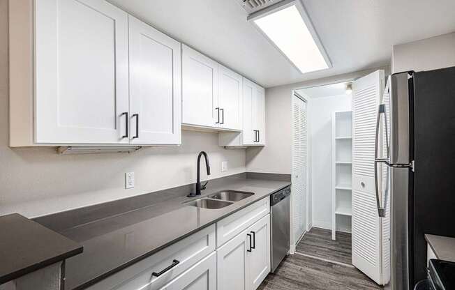 A kitchen with white cabinets and a black refrigerator.