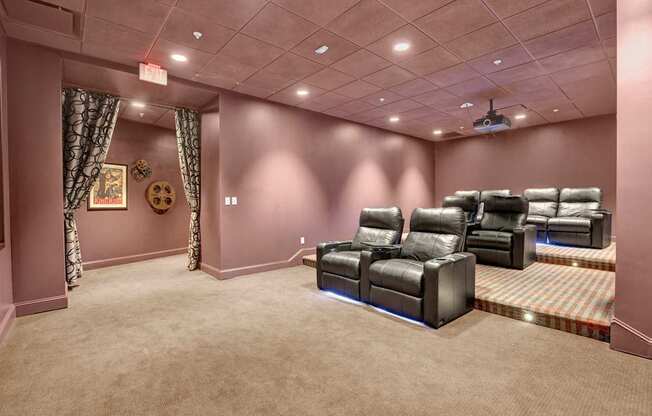 A home theater room with a carpeted floor and a row of black leather chairs.