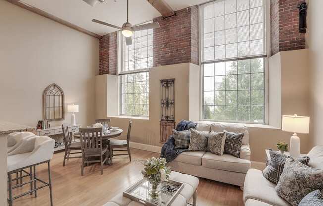 a living room with a couch and a table and a dining room with windows