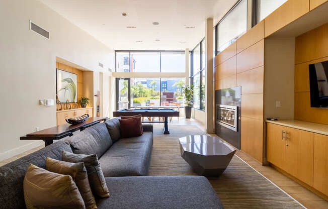 A modern living room with a grey couch and a large window.