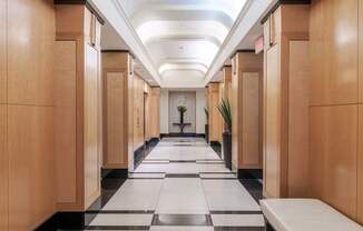 A long hallway with wooden doors and a checkered floor.