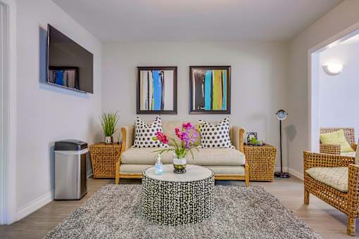 A living room with a sofa, a chair, a coffee table, and a TV.