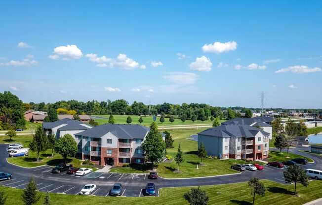 an aerial view of an apartment complex with a parking lot and a lake