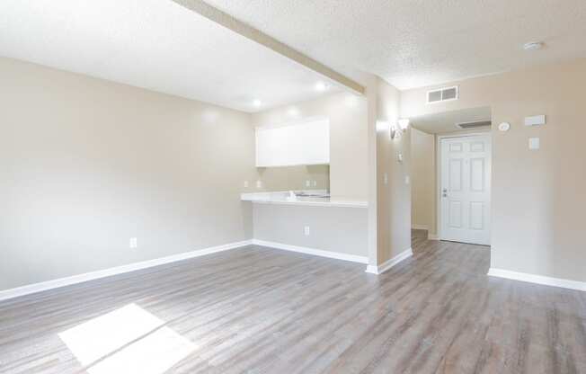 an empty living room and kitchen with wood flooring