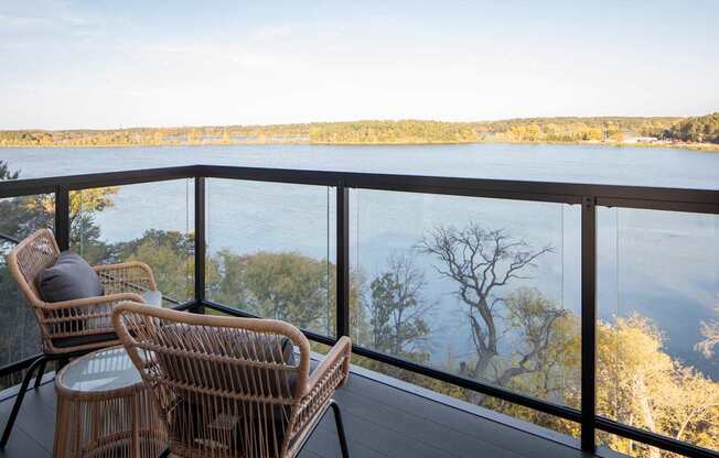 Two chairs are on a balcony overlooking a body of water.