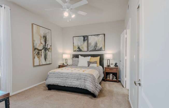 A bedroom with a bed, two lamps, and two framed pictures on the wall.