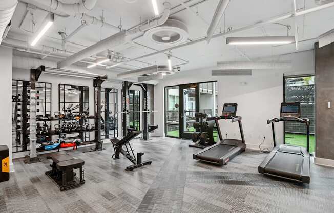 a workout room with treadmills and other equipment in a building with white walls at Link Apartments® Mint Street, Charlotte, NC