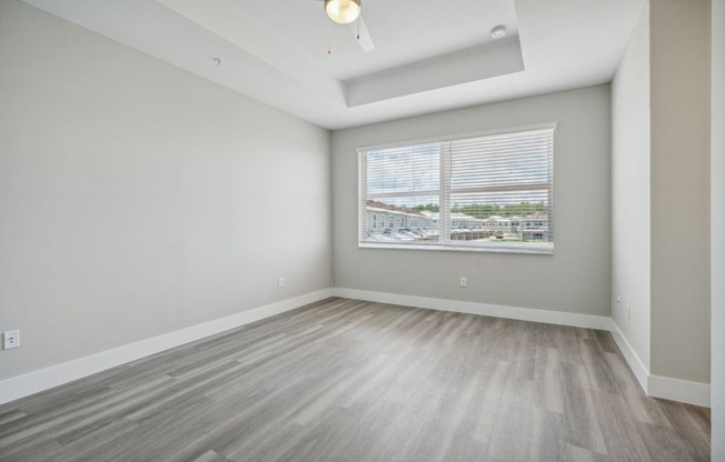 the living room of an apartment with wood floors and a large window