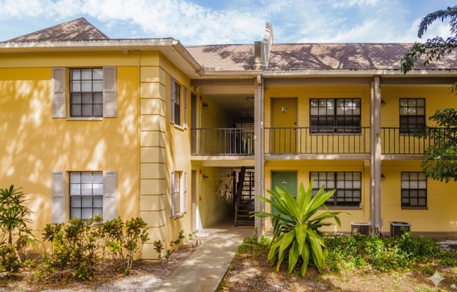 A yellow building with a green door and windows.