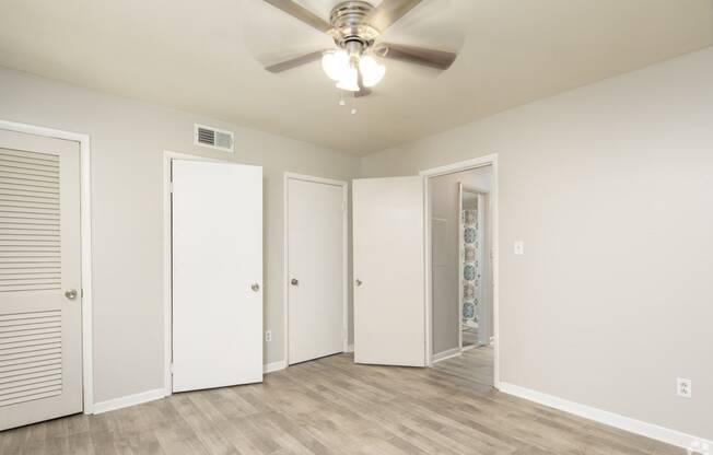 the living room of an empty apartment with a ceiling fan