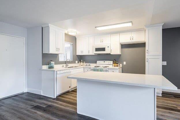 A kitchen with white cabinets and a white island.