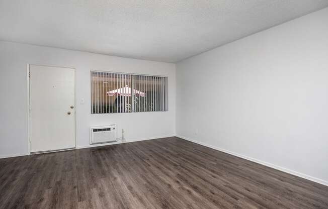 an empty living room with white walls and wood flooring