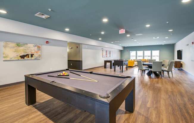 a pool table with tables and chairs in the background at The Vue apartments in Indianapolis