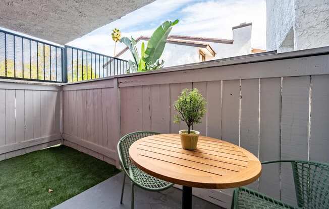 Fusion Warner Center apartments in Woodland Hills bottom floor patio with tall wooden fence, patch of lush grass, and modern patio table and chairs.