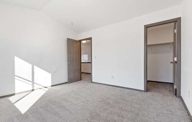 A large, empty room with a carpeted floor and a door on the right side.
