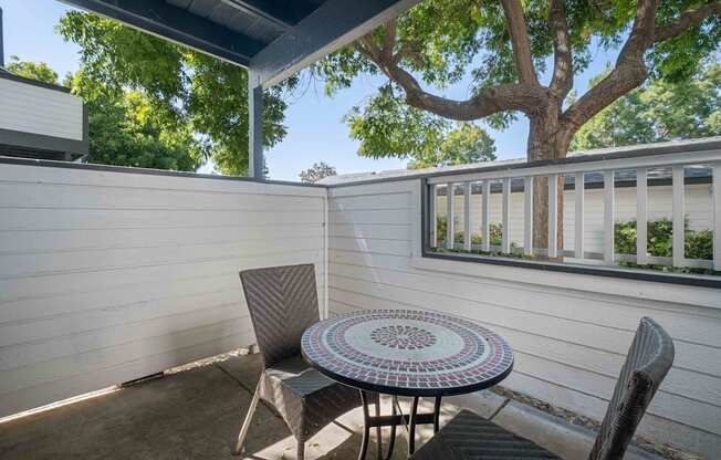 A patio with a table and chairs under a tree.
