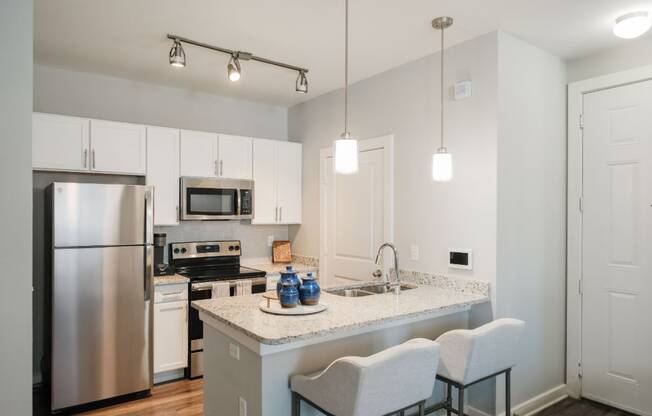 A kitchen with a stainless steel refrigerator, microwave, and oven.