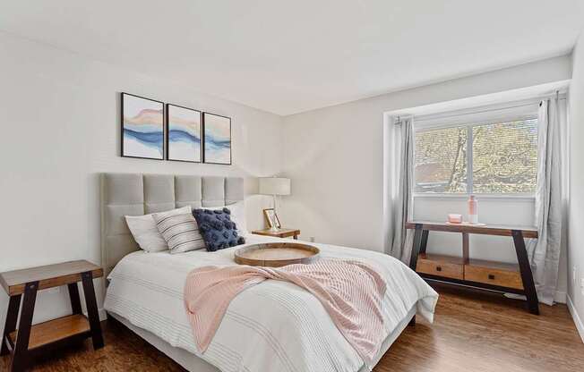 A bedroom with a large bed and a window overlooking a tree-lined street.