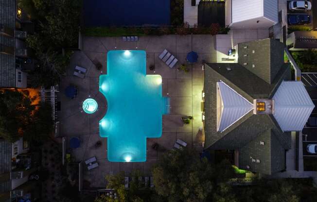 Nightime Drone of Pool Area with Lounge Chairs, Trees and Plants