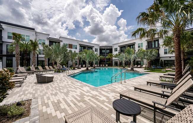 a swimming pool with palm trees in front of apartment buildings