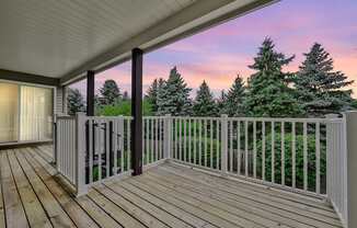 Pet-Friendly Apartments in Geneva, IL – Ashford at Geneva – A wooden deck with a white railing and a view of trees.