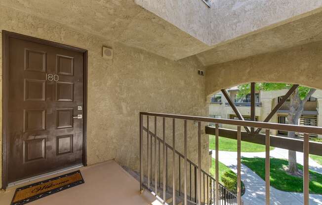 Second floor apartment entrance with staircase leading up to the brown front door