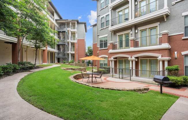 A sunny day at a residential complex with a green lawn and a small fountain.