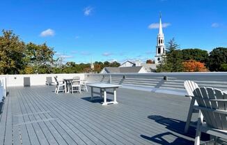 a roof deck with a table and chairs and a church in the background